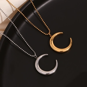 Detail of gold and silver crescent moon horn pendants on bead chains over black tray