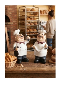 Macro detail of two resin chef figurines holding a pan and dough in a cozy bakery setting