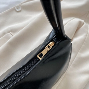 Chic black leather underarm bag featuring a smooth gold zipper and premium stitching