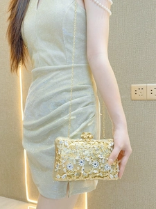 Detail of golden evening clutch with floral hollow metal patterns and blue crystals