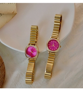 Detail of elegant gold quartz watch with vibrant rose red dial on vintage paper