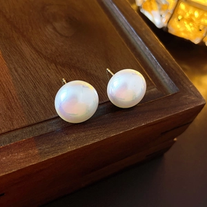 Vue macro de boucles d'oreilles perles blanches avec tiges dorées sur bois foncé