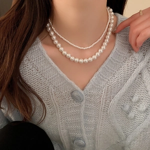 Gros plan d'un collier de perles à double rangée avec de grandes et petites perles blanches