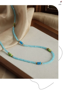 Détail du collier de perles fait main avec pierres facettées bleu ciel et accents dorés