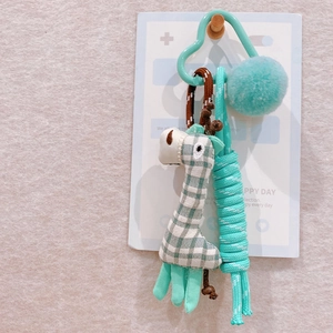 Close-up of handmade green checkered fabric giraffe keychain with braided rope and soft pompom