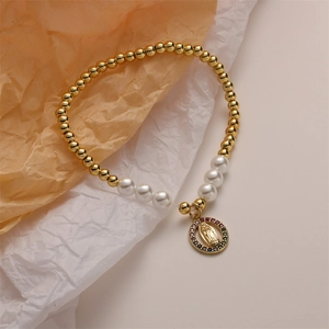 Detailed view of elastic gold beads and pearl bracelet with a religious Virgin Mary charm