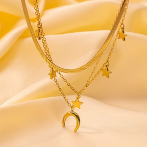 Detail of layered gold-plated necklaces with star and crescent moon pendants on silk