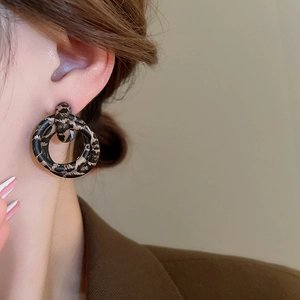 Close-up of a model wearing retro leopard print double hoop earrings in matte brown finish