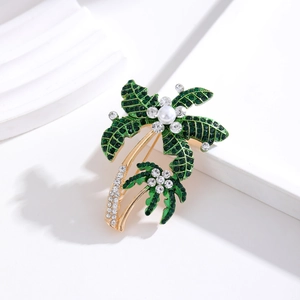 Elegant gold coconut tree brooch with green crystals and small white pearls on white background