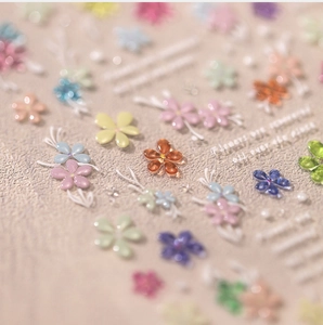 Macro shot of 3D embossed floral nail art stickers with colorful resin flowers and pearls