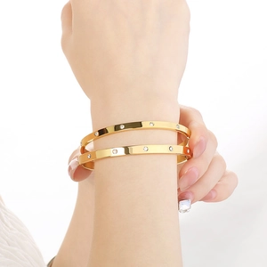 Fashionable gold stainless steel bracelets with sparkling crystals stacked on wrist