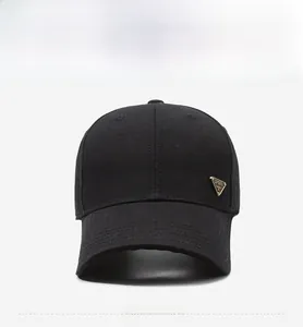 Detail of black baseball cap featuring a golden triangular metal SPORT logo and curved brim