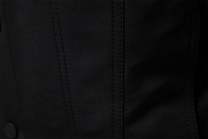 Dettaglio macro del tessuto twill nero con doppia cucitura e bottone opaco della giacca