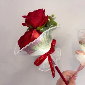 Detail shot of a red artificial rose pen with LED light and Love ribbon decoration