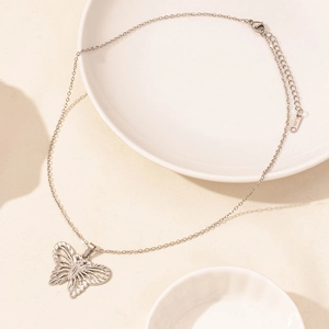 Detailed view of silver butterfly pendant necklace with intricate cut-outs on textured surface