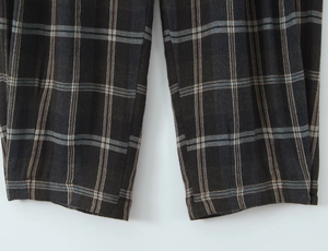 Detailed macro view of the dark grey plaid fabric texture and hem on these trousers