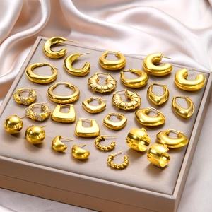 Collection of golden geometric earrings on silk tray with hoops and studs detail