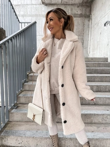 Detail of white plush coat with metallic chain bag and boots on concrete steps