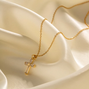Detail eines 18K vergoldeten Kreuzanhängers aus Edelstahl mit Zirkonia auf Seidenstoff
