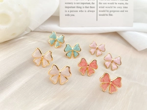 Detail of bow earrings with marble texture enamel oil drops in multiple pastel colors
