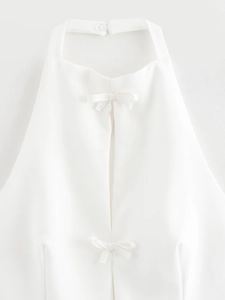 Close-up of white halter top neck detail with bow decoration and button closure