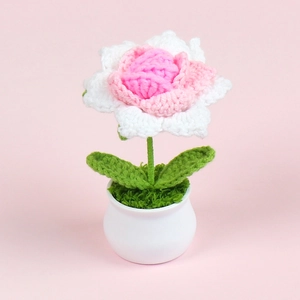 Close-up of handmade crochet rose in a white ceramic pot with soft pink background