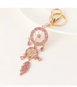 Macro detail of golden dreamcatcher keychain with pink crystals on white plate