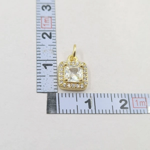 Macro view of gold pendant showing square zircon dimensions with a metric ruler