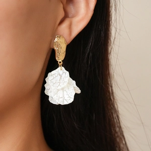 Close-up of bohemian gold irregular stud earrings with white petal pendants on a model