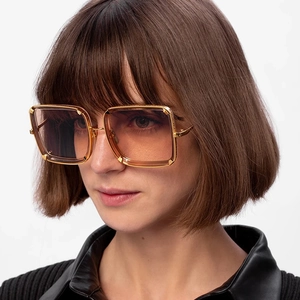 Close-up of golden square metal frame sunglasses with orange gradient lenses on model
