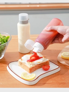 Detailed view of clear plastic squeeze bottle with 5-hole nozzle dispensing red sauce