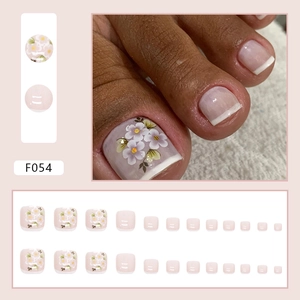 Pink French toe press-on nails with white floral patterns and green leaf accents