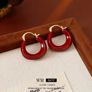 Modern Ancora red U-shaped gold-plated hoop earrings on a vintage velvet display tray