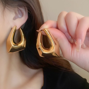 Détail macro de boucles d'oreilles géométriques dorées montrant le lustre métallique