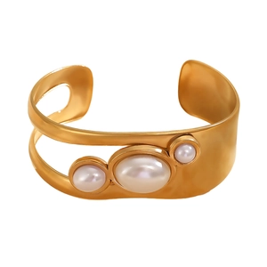 Detail of matte gold open bangle featuring three oval pearls in a hollowed design
