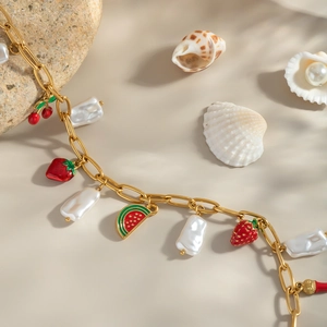 Collier doré avec pendentifs fraise cerise pastèque et perles baroques sur le sable