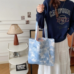 Dettaglio borsa tote in tela tie-dye blu con tasca frontale in un ambiente interno retrò