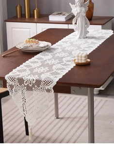 Detail of white lace table runner with intricate floral patterns and elegant tassel fringe