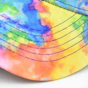 Close-up of tie-dye baseball cap brim with multi-color canvas texture and reinforced stitching