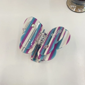 Detail of butterfly claw clip with blue and purple striped acetate and rhinestone accents
