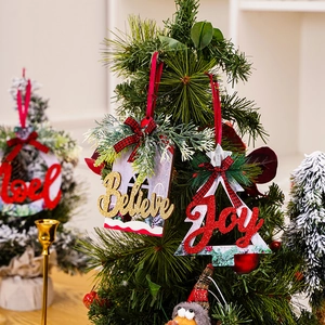 Close-up of wooden glitter Believe and Joy letter ornaments hanging on a green Christmas tree.