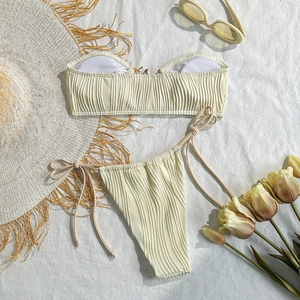 Detailed view of cream ribbed bikini set with side-tie bottoms and beach accessories