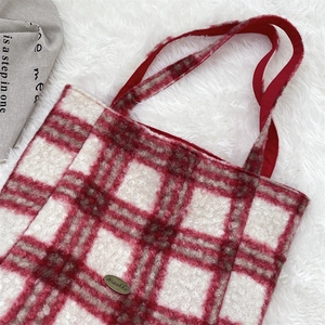 Close-up of red and white checkered lamb wool tote bag with soft texture and metal logo