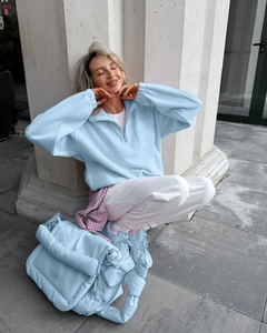 Detail of light blue fleece sweatshirt and matching quilted padded crossbody bag