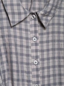 Close-up of classic grey plaid shirt collar and translucent buttons on a high-quality fabric