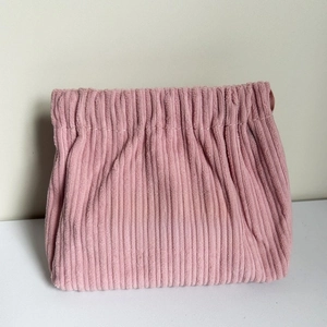 Detailed texture of pink corduroy cosmetic pouch with Free Travel woven label
