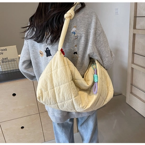 Detailed view of beige quilted nylon tote bag with knot strap and purple charm