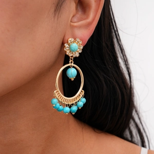Close-up of bohemian tassel earrings with blue turquoise stones and rhinestones on a model