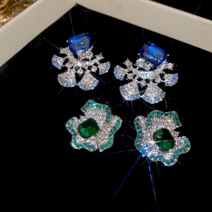 Macro shot of luxury fan-shaped earrings with blue and emerald gemstones and crystals