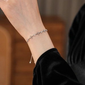 Detailed close-up of a silver zircon cross bracelet with adjustable drawstring closure